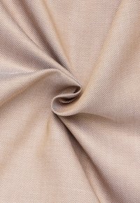 Tessuto beige testurizzato con un fine motivo tessuto, che mostra una leggera lucentezza e una finitura liscia, drappeggiato per evidenziare pieghe e contorni naturali.
