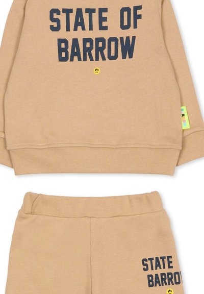 Beżowy zestaw dresowy ze sweatshirtu i spodni z napisem "STATE OF BARROW" w kolorze granatowym. Posiada mały żółty uśmiech i kolorową metkę z boku.