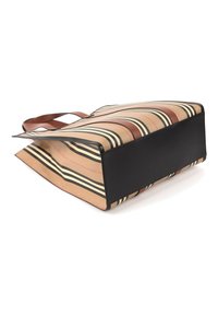 Grand cabas avec des rayures beiges, noires et blanches, des anses marron et une base noire unie posé à plat sur une surface blanche.