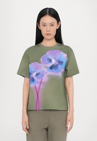 Olivgrünes T-Shirt mit kurzen Ärmeln, das mit großen blauen und lila Blumenmotiven bedruckt ist. Weicher Stoff mit lockerer Passform und Rundhalsausschnitt.