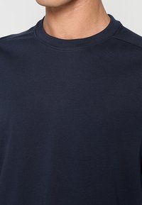 Marineblauw katoenen T-shirt met ronde hals, gladde textuur en korte mouwen. Heeft minimale stiksels en een eenvoudig, klassiek ontwerp.