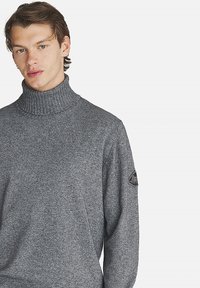 Maglione grigio in lana con colletto a dolcevita e maniche lunghe. Presenta un motivo testurizzato e un'etichetta con logo sulla manica sinistra.