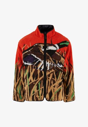 Polarowa kurtka z wysokim kołnierzem, w pomarańczowym kolorze, z grafiką kaczki wśród brązowych i zielonych wzorów trawy. Czarny zamek błyskawiczny.