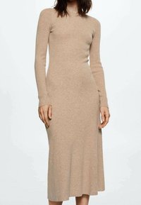 Robe en maille côtelée à manches longues de couleur beige clair. Silhouette ajustée avec un col montant et un ourlet mi-long, offrant une texture lisse.