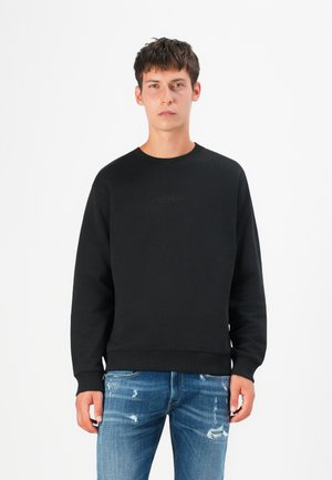 Black sweatshirt with a crew neckline, ribbed cuffs, and hem. Features embossed "REPLAY" logo on the front. Paired with distressed blue jeans.