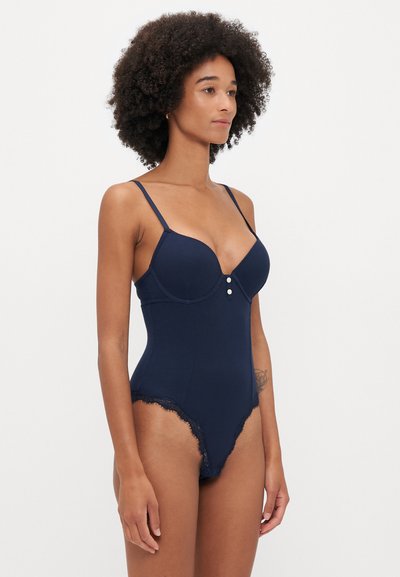 Body azul marinho com acabamento em renda e textura canelada, apresentando alças ajustáveis e um decote profundo com dois botões decorativos.