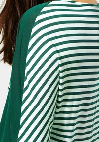 Randig grön och vit topp i lätt tyg, med avslappnad passform, kontrasterande enfärgade gröna ärmar och rund halsringning.