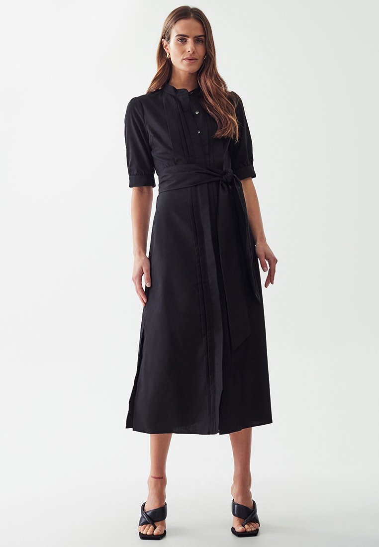 Abito maxi nero in tessuto leggero, con maniche corte, una chiusura frontale con bottoni, dettagli plissettati e una cintura coordinata in vita.