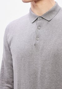 Tricou polo cu mâneci lungi, gri, realizat din material moale, cu guler clasic și fante cu patru nasturi. Textură netedă și design simplu.