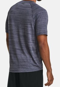 Kurze Ärmel Sportshirt in Dunkelblau mit einem strukturierten, melierten Muster. Verfügt über Raglanärmel und ein kleines Logo auf der Rückseite.