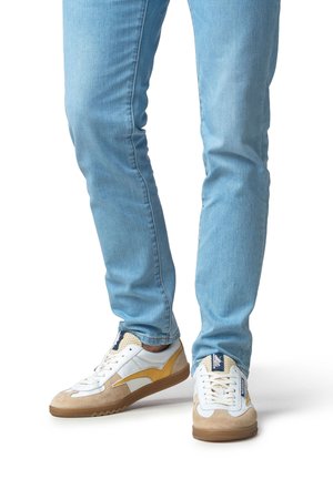 Sneakers with a combination of white leather, beige suede, and yellow accents. Rubber sole with zigzag pattern, lace-up design, and logo.