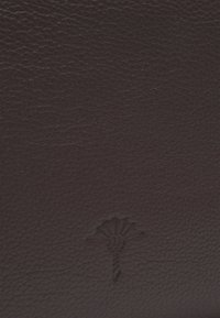 Brązowa skóra z fakturowaną powierzchnią i wytłoczonym motywem kwiatowym na dole, prezentująca bogaty, głęboki kolor i subtelny wzór.