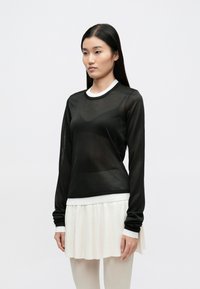 Must mustriline läbipaistev pikkade varrukatega särk ümarate kaelustega ja valgete soonikkoes ääristega, millele on kombineeritud volditud valge seelik. Pehme, kerge kangas.