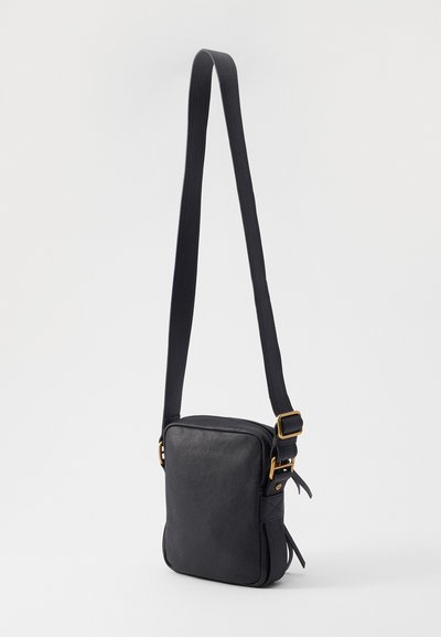 Černá kožená křížová taška čtvercového tvaru, s nastavitelným popruhem, zlatými kovovými detaily a hladkým povrchem.