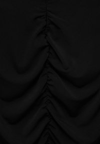 Tissu noir avec fronces verticales réunies créant des plis texturés le long de la ligne centrale.