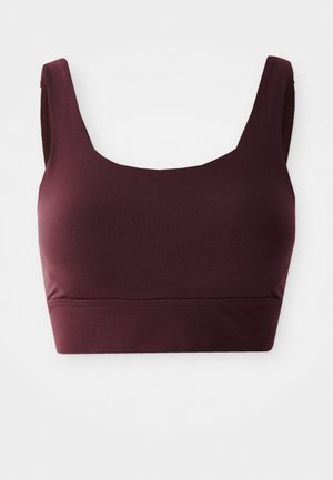 Soutien-gorge de sport bordeaux avec un décolleté plongeant, des bretelles larges et une coupe ajustée, fabriqué à partir d'un tissu doux et extensible. Pas de matériel visible.