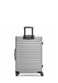 Silberner Hartschalenkoffer mit strukturiertem Design, ausgestattet mit horizontalen Rillen, einem ausziehbaren Griff und vier Rädern für Mobilität.