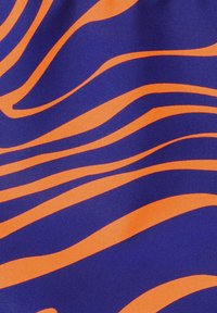 Mėlynas audinys su ryškiomis oranžinėmis banguotomis juostomis. Dizainas pasižymi sklandžiomis linijomis, kontrastingomis spalvomis ir subtiliu blizgesio tekstūra.