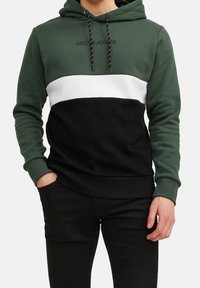 Sudadera con capucha en bloques de color verde, negro y blanco, con cordón ajustable en la capucha y un logotipo en el pecho; hecha de una tela suave y texturizada.