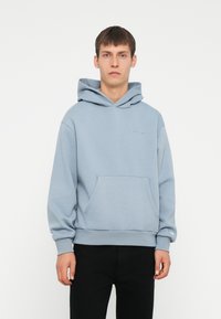 Felpa blu chiaro in misto cotone, con tasca a marsupio frontale e polsini a coste, con un discreto logo ricamato sul petto.