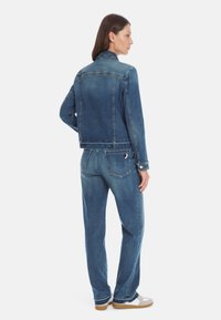 Denim jacket and pants set in medium blue. Jacket is cropped with a straight fit. Pants are wide-legged with a slightly distressed effect.