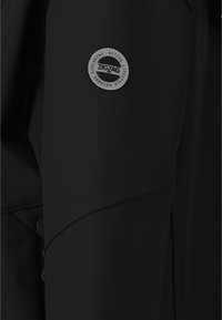 Veste de sport noire avec un écusson circulaire gris portant l'inscription "ZIGZAG" sur la manche, texture lisse et design épuré.