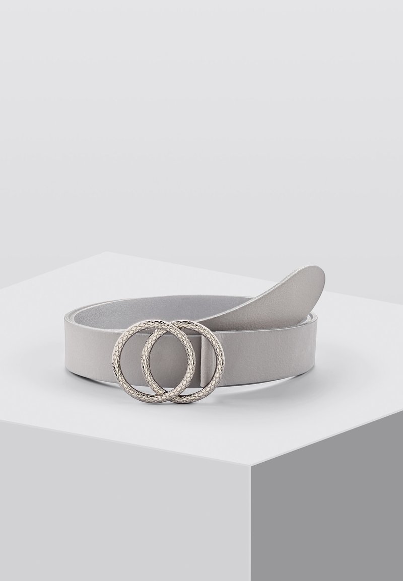 Ceinture en cuir gris clair avec une boucle double anneau argentée texturée, enroulée sur une surface blanche contre un fond gris uni.