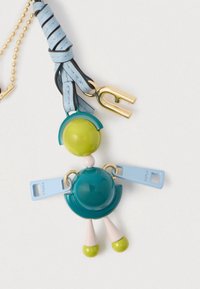 Privjesna figura s tijelom u obliku zelene i tirkizne sfere, svijetloplave kožne narukvice, zlatnog kopčanja i svijetloplave navlake za zatvarač na bijeloj pozadini.