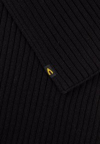 Zwarte ribgebreide stof met een omgekrulde zoom en een klein zwart label met een geel logo. Gevoelige structuurdetails zichtbaar.