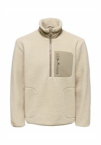 Kermansävyinen fleeceneule korkealla kauluksella; varustettu etuvetoketjulla, yhdellä vetoketjullisella taskulla ja kahdella suurella sivutaskulla. Kangas on teksturoitua pintaa.