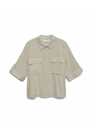 Chemise beige à boutons avec large col, deux poches à rabat à l'avant et manches mi-longues retroussées avec pattes à boutons.