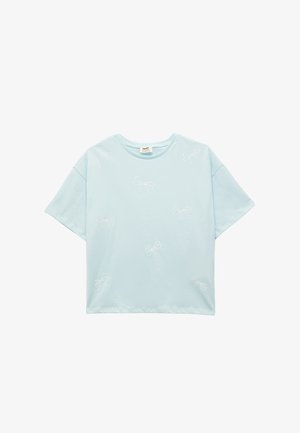 Lyseblå bomulds t-shirt med korte ærmer, prydet med hvide broderede sløjfemønstre jævnt fordelt over stoffet. Rund udskæring.