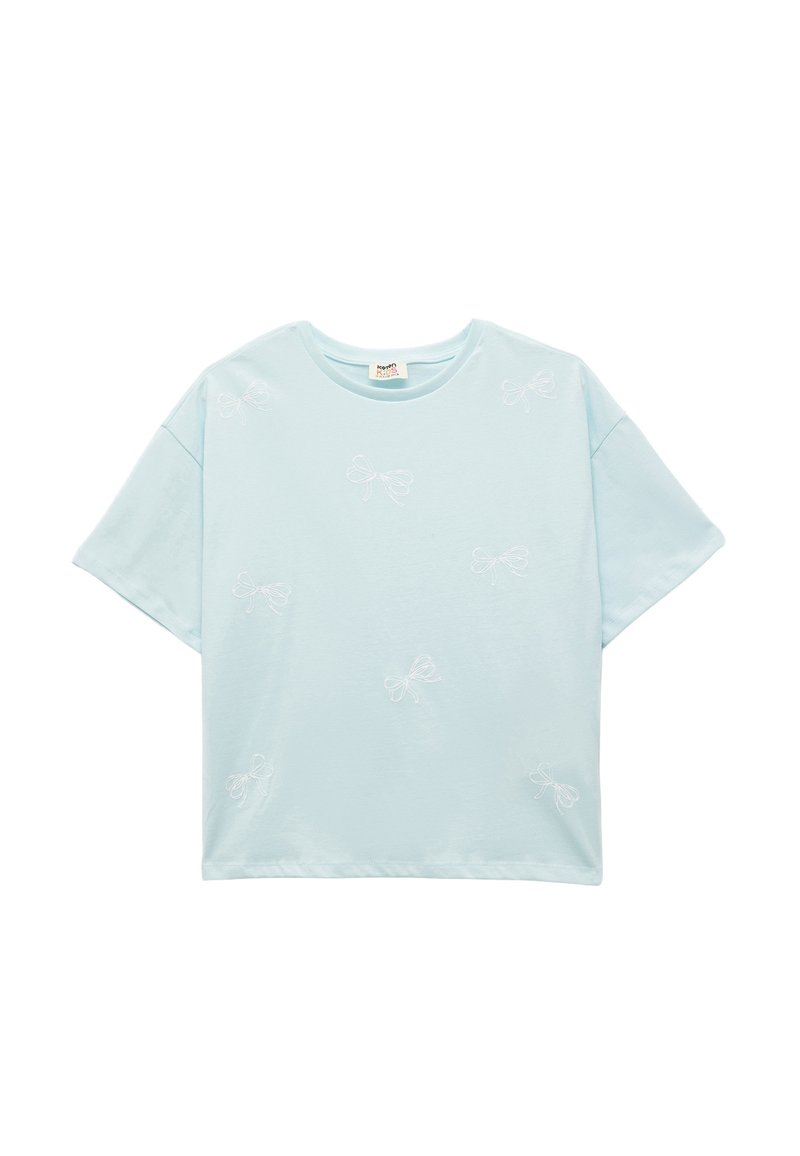Camiseta de algodón azul claro con mangas cortas, que presenta patrones de lazo bordados en blanco distribuidos uniformemente por toda la tela. Cuello redondo.