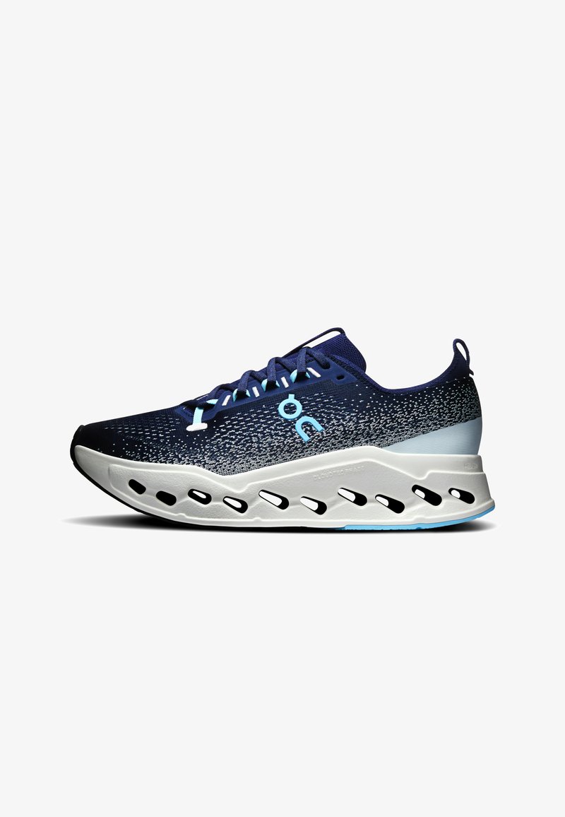 Chaussure de sport bleu marine et blanche avec dessus en maille, fermeture à lacets, logo bleu clair, et semelle blanche coussinée avec détails découpés noirs.