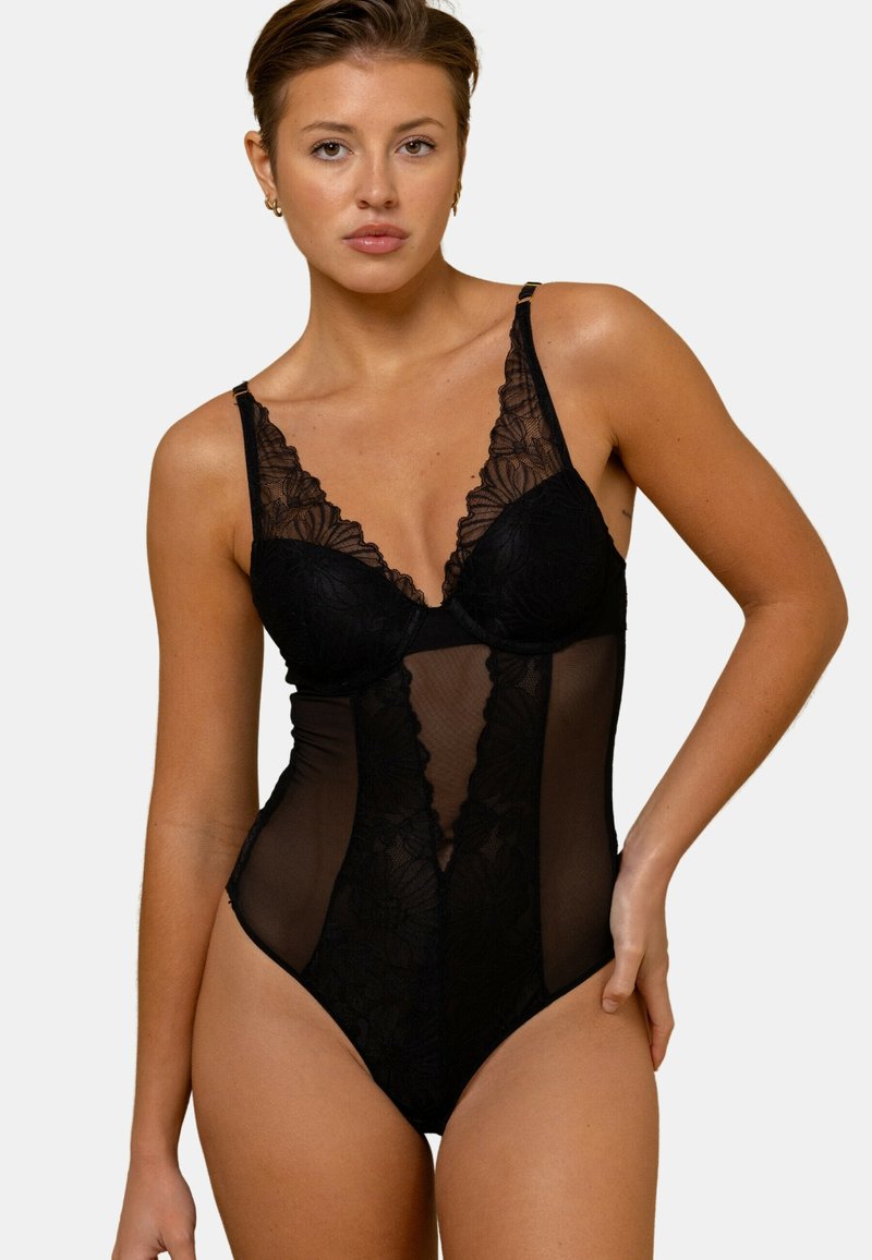 Body en dentelle noire avec tissu transparent, présentant un col en V profond, un motif floral et des bretelles réglables. Silhouette cintrée et coupe haute.