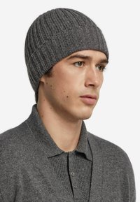 Gray ribbed knit beanie made of soft material, fitted closely to the head, with a subtle texture and seamless top construction.