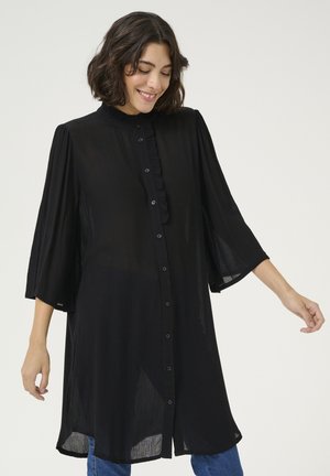 Chemise noire à boutons avec un col volanté, des manches cloche trois quarts et une texture légère. Présente une légère forme en A et un tissu transparent.
