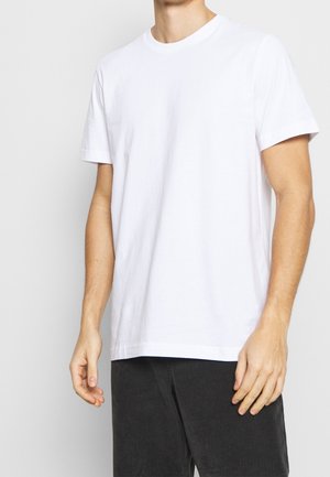 Biały bawełniany t-shirt z krótkim rękawem, okrągłym dekoltem i luźnym krojem. Gładka faktura, minimalistyczny design, pasuje do ciemnych spodni ze sztruksu.