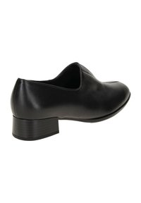 Chaussure en cuir noir avec un bout arrondi, un petit talon bloc, et une texture lisse, présentant une couture discrète le long du bord supérieur.