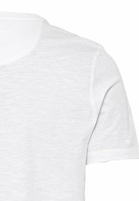 Witte korte mouwen t-shirt met een ronde hals, zachte, licht gestructureerde stof en zichtbare stiksels langs de randen.