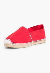 Espadrille en toile rouge avec un bout rond, semelle en jute et couture blanche le long des bords. Design simple, à enfiler, sans embellissements.