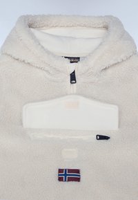 Krämfärgad fleece-pullover med halvmask, kenguruficka och ett isländskt flaggpatch på framsidan. Mjuk textur och mysig design.