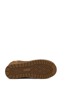 Brauner Wildlederstiefel mit einer strukturierten Gummisohle, die ein Schneeflockenmuster aufweist. Die Sohle hat ein Traktionsdesign für besseren Halt.