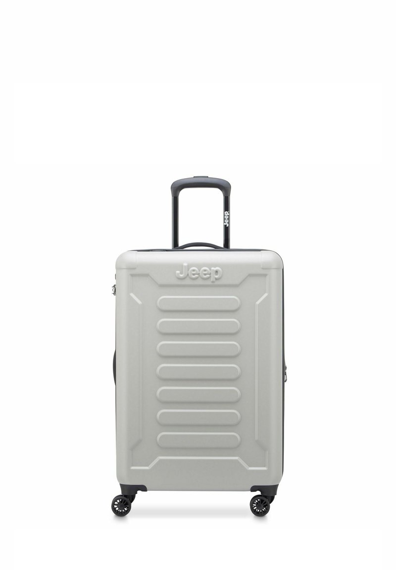Valise rigide Jeep de couleur gris clair, avec des rainures verticales, une poignée noire rétractable et quatre roues pivotantes noires.