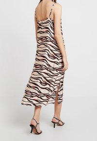 Maxime dress i ljusrosa med ett zigzag-mönster i svart och röd, med tunna axelremmar, en sidodel och en lös passform för enkel rörelse.