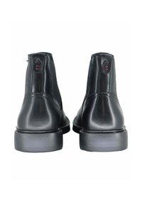 Czarne skórzane botki za kostkę o gładkiej fakturze, z elastycznymi panelami po bokach i grubą gumową podeszwą. Posiadają małe logo oraz ozdobne przeszycia.