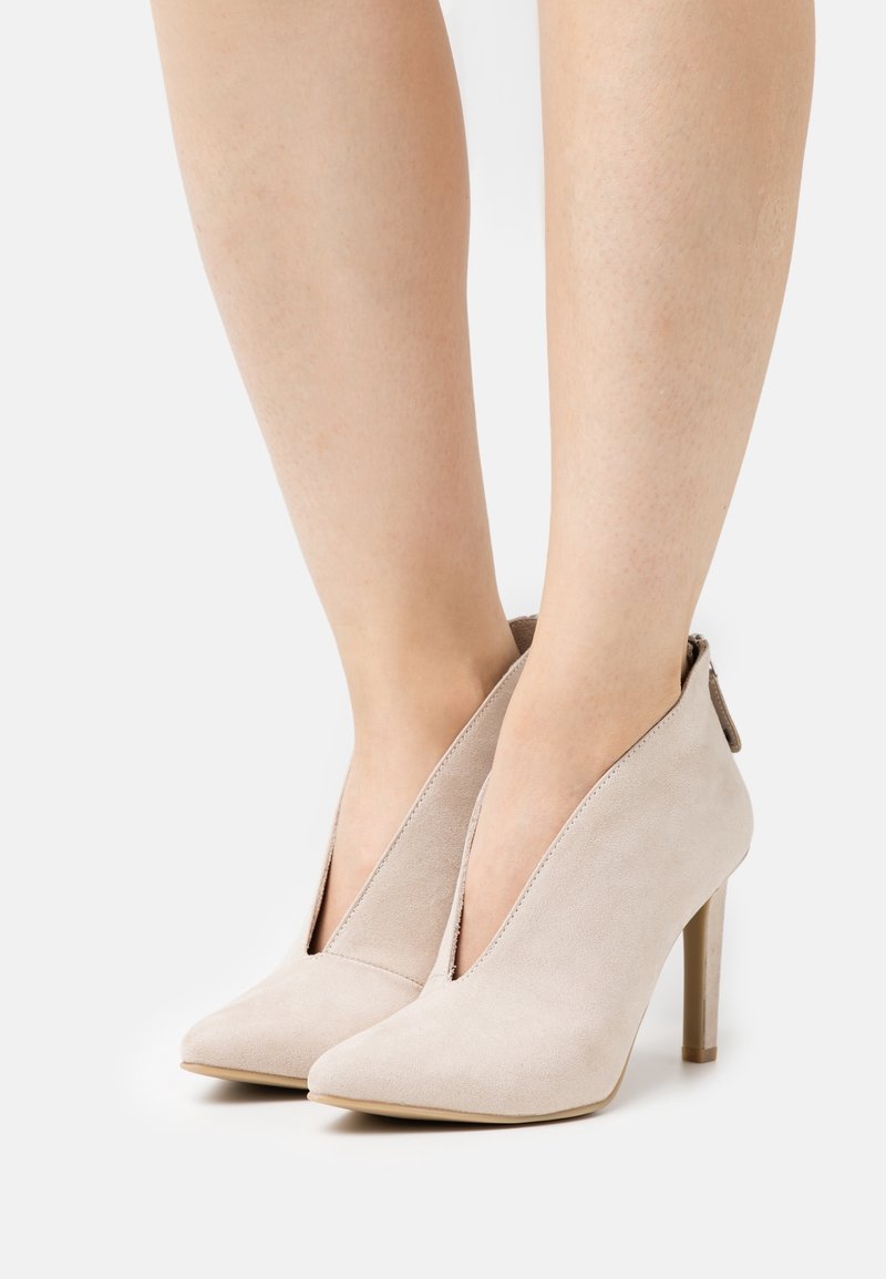 Beige semišové lodičky na vysokém podpatku s špičatou špičkou, bočními výřezem a úzkým podpatkem. Design je elegantní s minimem detailů.