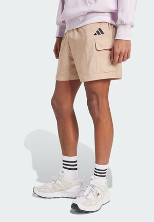 Tan cargo shorts with side pocket, black accents, featuring striped white and black socks and white athletic shoes. Smooth fabric texture.