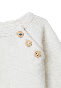 Lichtbeige sweatshirt met een ronde hals, voorzien van drie grote houten knopen met blauwe accenten op de schouder. Zachte textuur.