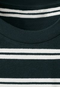 Gros plan sur un tissu tricoté à rayures horizontales noires et blanches avec un col arrondi.